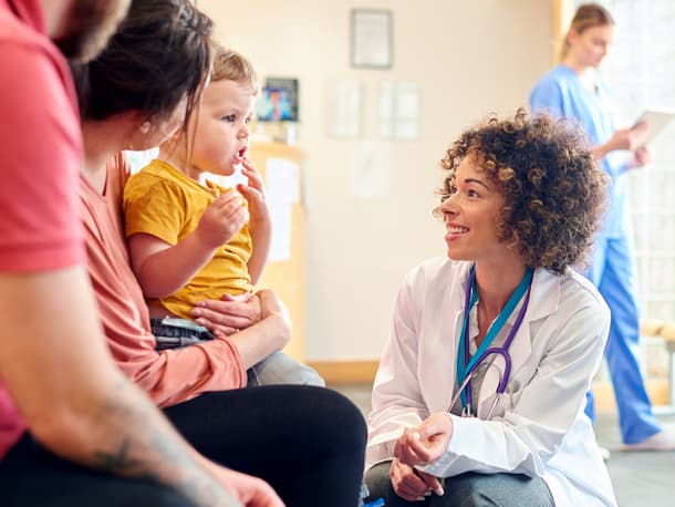 Female doctor talking to couple with young child